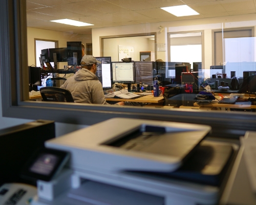 Man in grey sweater working on he computer at a desk