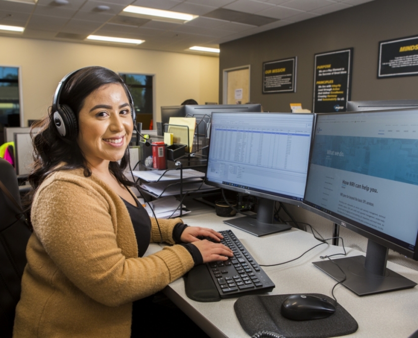 Woman with headset at desk working on a computer